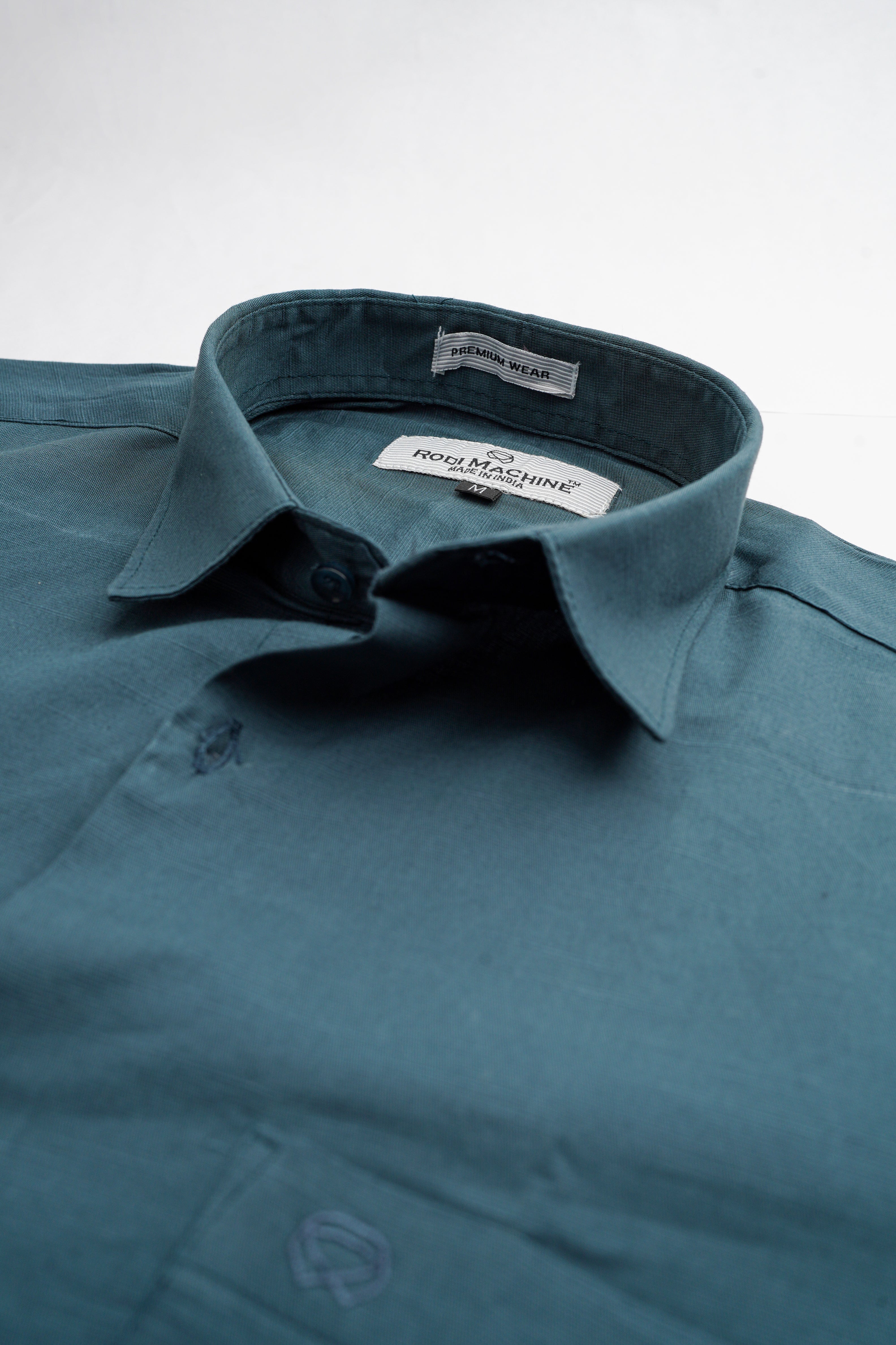Peacock colour Rodi Machine shirt with a brand label on a light gray background