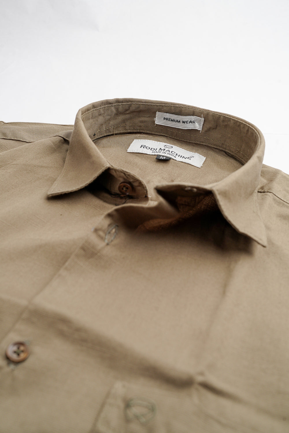 Close-up of a Kakhi colour Rodi Machine shirt with a visible brand label on a white background