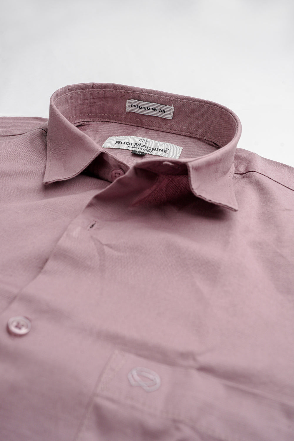 Close-up of a Lavender colour Rodi Machine shirt with a brand label on a light gray background