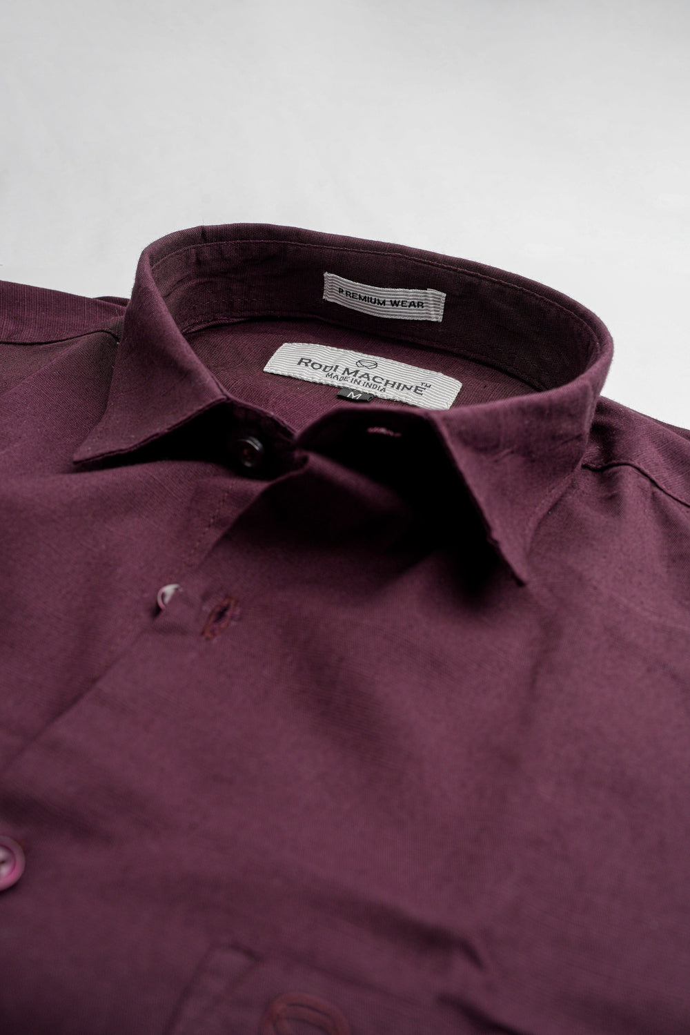 Close-up of a Purple colour Rodi Machine shirt with a brand label on a light gray background